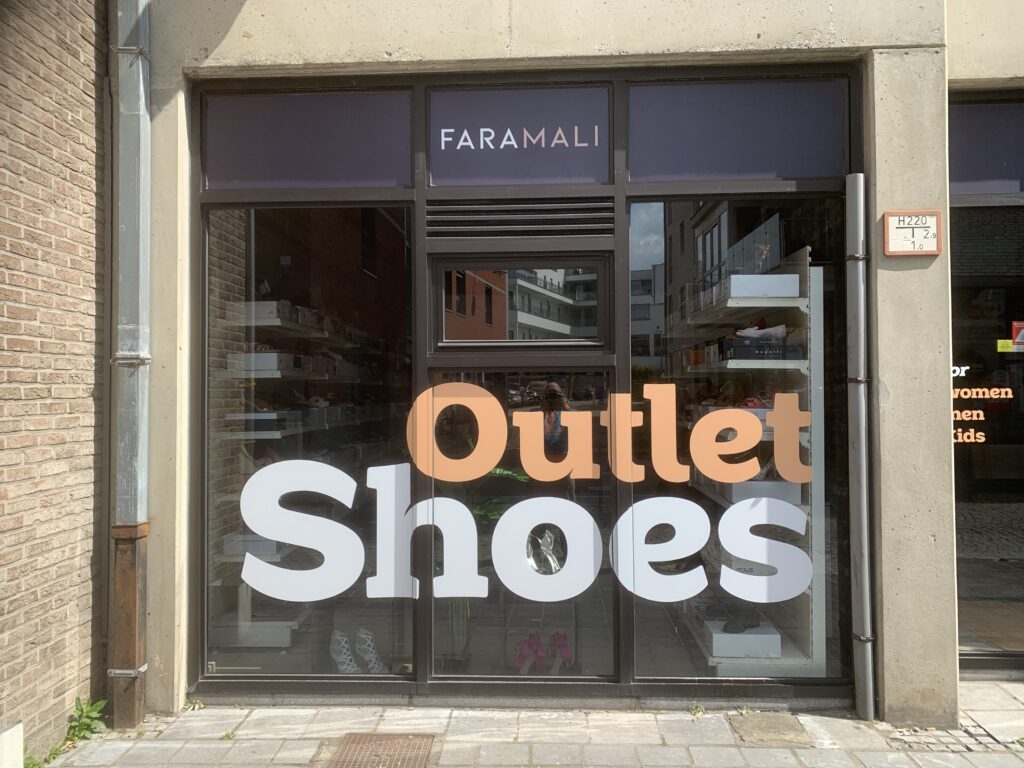 Lettrage publicitaire de la vitrine Outlet Shoes réalisé par ADLCOM